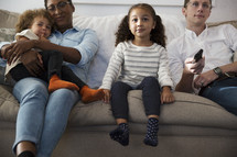 a family sitting on a couch watching tv together 