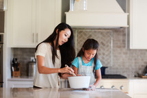a mother and daughter cooking in a kitchen 