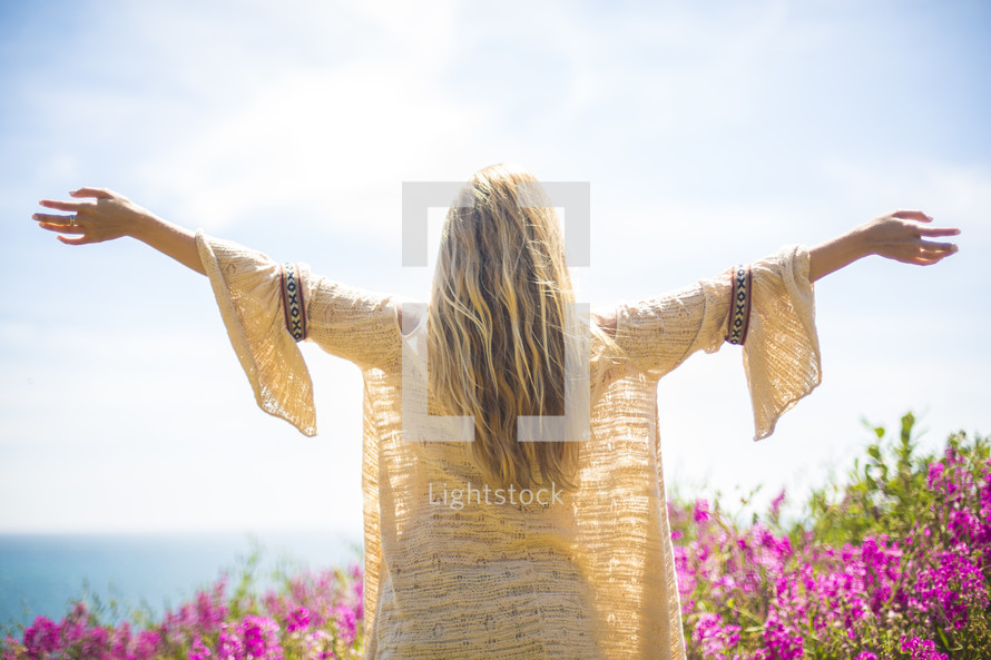A blonde woman with arms raised towards the sky.