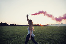 young woman walking holding a smoke flare 