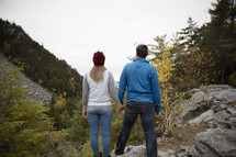 couple holding hands standing on a mountain 