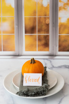 Thanksgiving place setting with the word blessed in front of a kitchen window