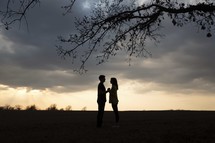 silhouette of a couple holding hands at sunset 