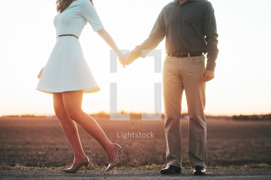 a couple holding hands standing on a rural road 