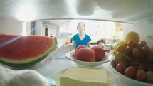 POV shot from inside a refrigerator of kids opening the door and taking out food