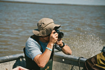 man taking a picture with a camera on a boat 