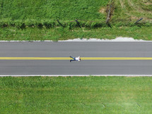 a man lying in the middle of a road from overhead 