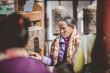 women praying at a prayer wheel in Nepal