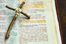 Rustic handmade cross laying by John 15:13 scripture in Bible that says, "Greater love has no one than this, that one lay down his life for his friends."