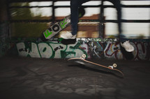 Feet and skateboard midair in grafitti garage.