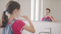 Little girl brushing her teeth in the bathroom in the morning