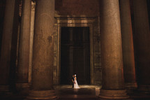 bride and groom between columns in the lobby of an elegant building