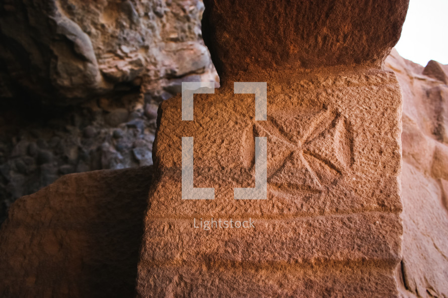 Cross symbol etched in the stone entrance to Lot's cave near the Dead Sea, Jordan.