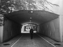man walking through a tunnel 