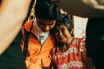 young man comforting an elderly woman 