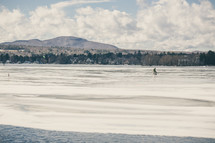 a man sitting on a frozen lake ice fishing 