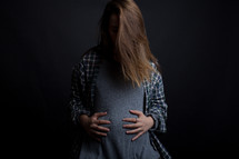 A pregnant teenager holding her stomach.