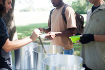 serving soup at a soup kitchen outdoors 
