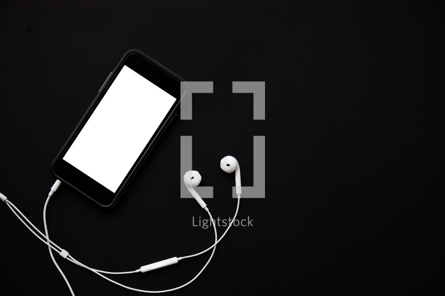 cellphone with earbuds against a black background 