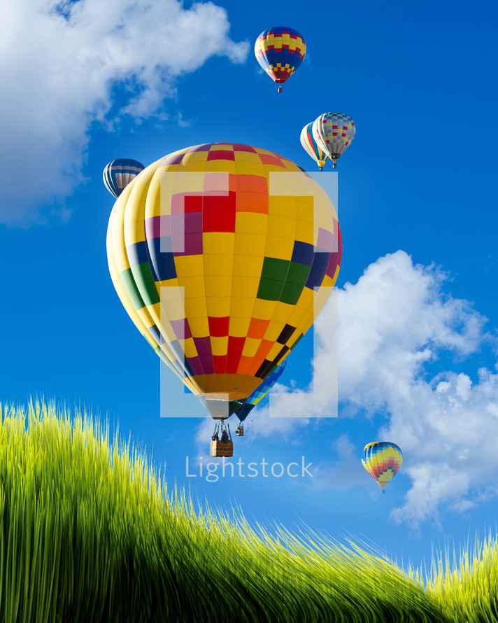 rising hot air balloons in a blue sky and green grass 