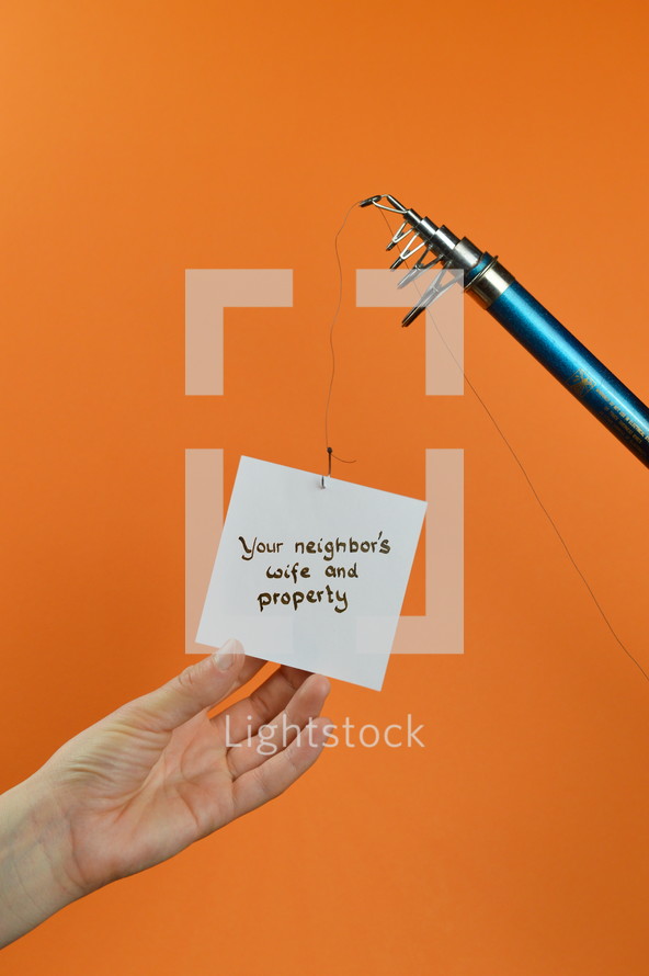 a hand reaching for a piece of paper with the words YOUR NEIGHBOR'S WIFE AND PROPERTY on it hanging from a fishing line 