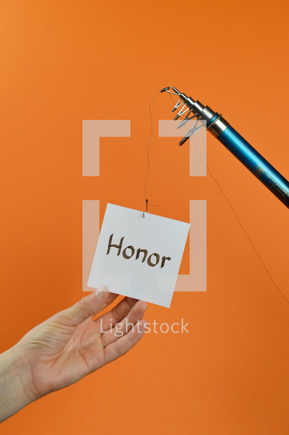 a hand reaching for a piece of paper with the word HONOR on it hanging from a fishing line 