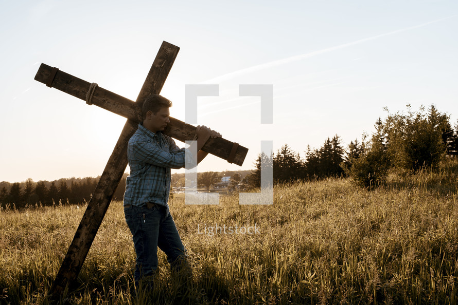man carrying the cross through a field 