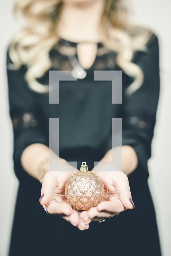 woman holding a gold Christmas ornament 