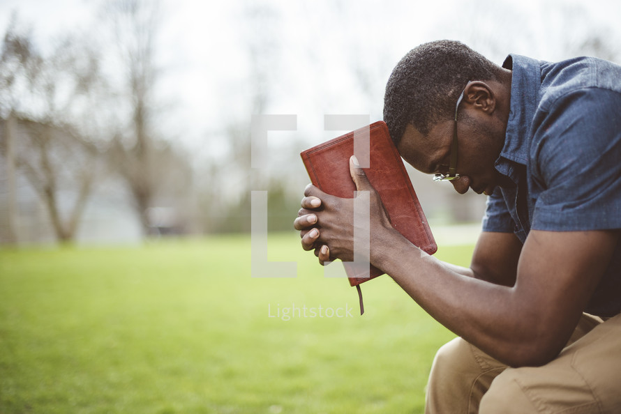 a man praying holding a Bible 