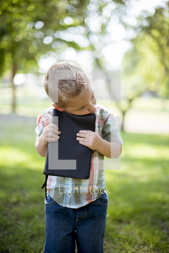 toddler boy hugging a Bible 