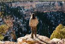 a man standing at the edge of a cliff looking down 