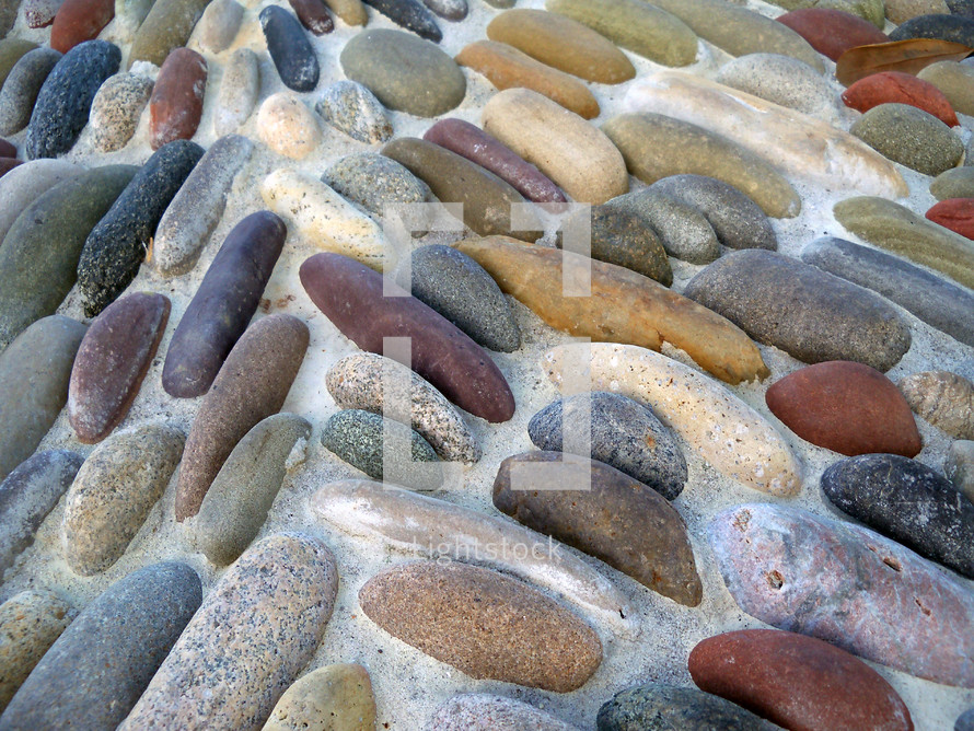smooth stone background walkway in an outdoor garden with smooth stones embedded in concrete. 