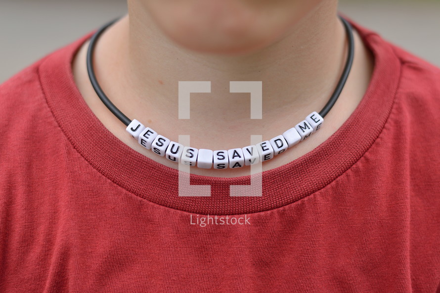 JESUS SAVED ME written on beads at a necklace around a kids neck. 