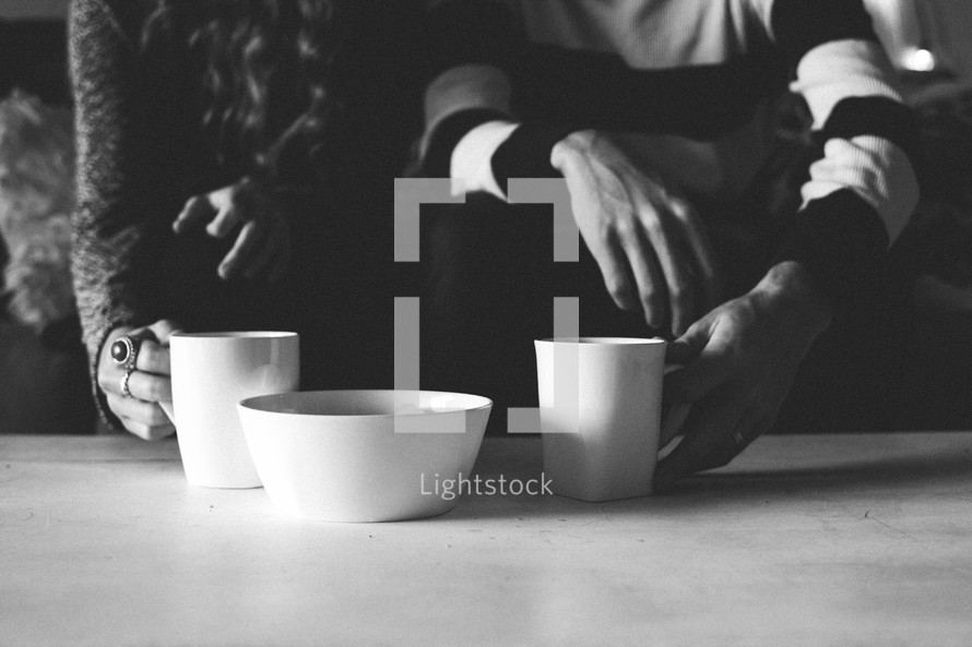 a couple with coffee mugs on a table 