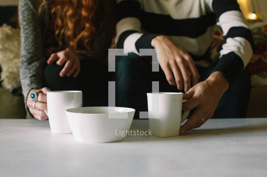 couple with coffee mugs on a coffee table 