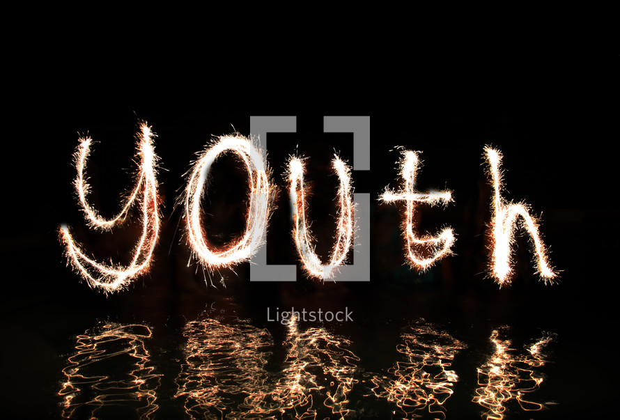 The word 'Youth' written in fireworks (by five 'artists' standing in waist high water).
