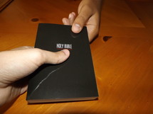 Hands passing a Holy Bible.