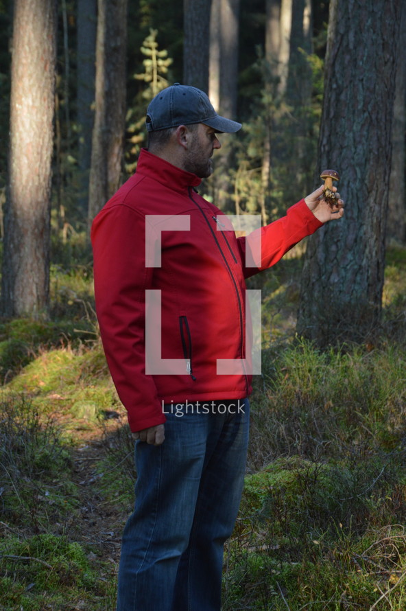 man holding a mushroom in a forest 