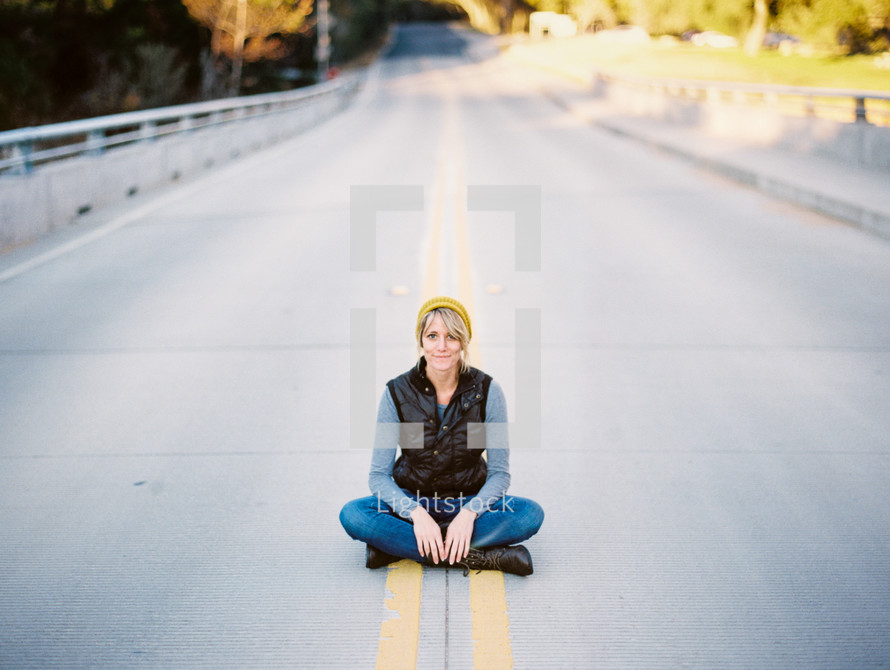 woman sitting in the middle of a road 