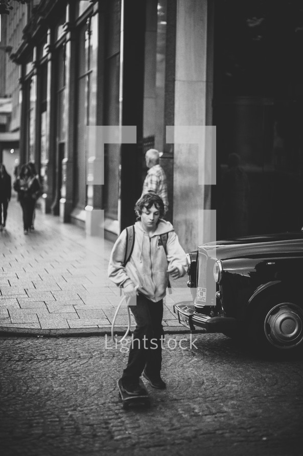 Boy riding a skateboard across a cobblestone street.
