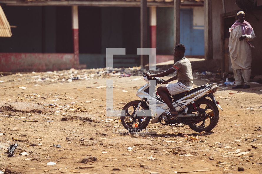 African men driving a motorcycle a small village in the Ivory Coast in west Africa