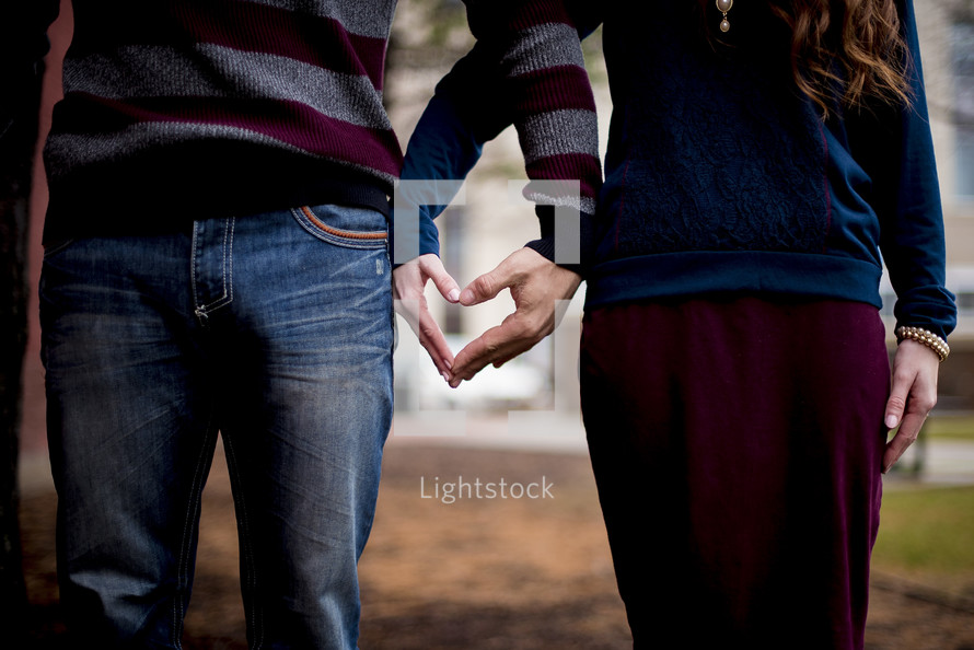 couple making a heart shape with their hands 