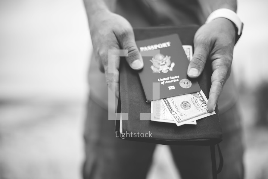 man holding a passport, cash, and Bible 