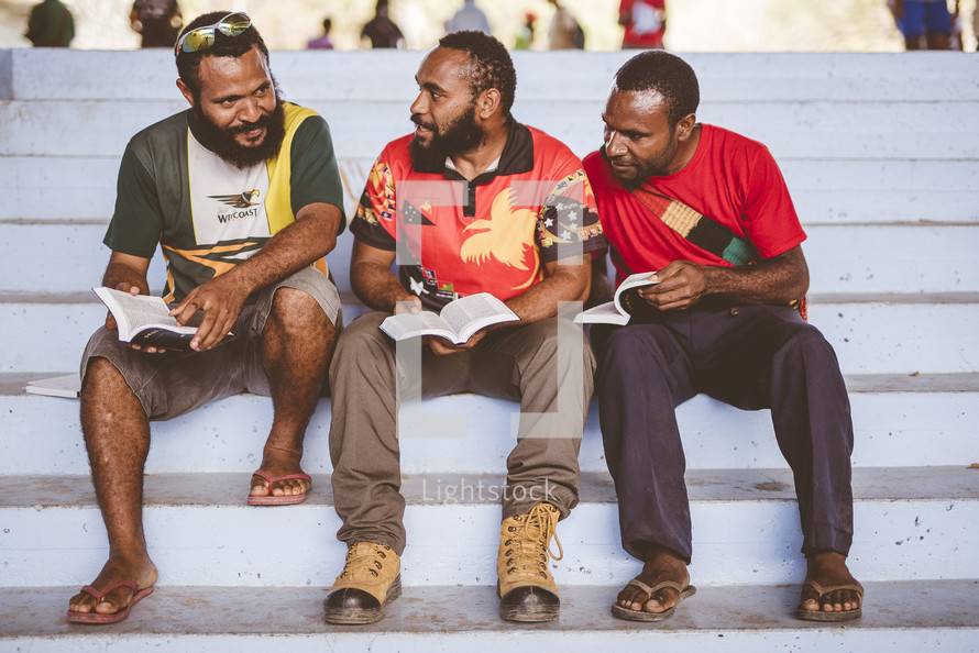 men sitting on steps reading a Bible 