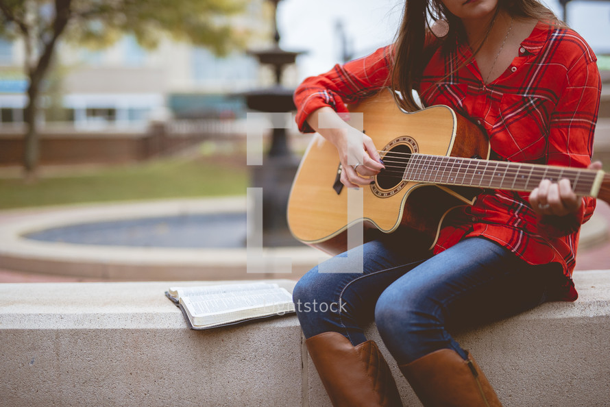 woman playing a guitar and reading a Bible 