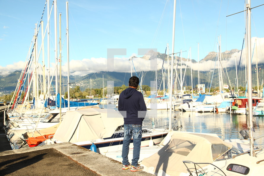 man standing on the docks at a marina 