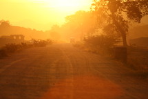 glow of the sun at sunset over a dirt road 