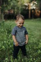 a toddler boy standing in grass