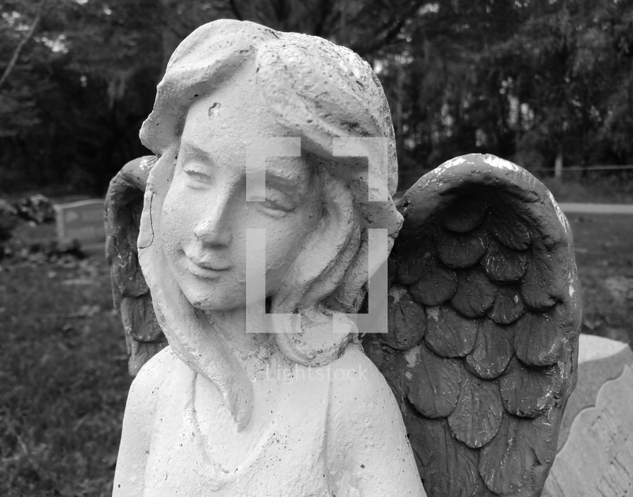 Smiling stone angel in a graveyard - black and white