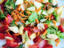 A salad mixed with fruit and vegetables to be part of a healthy diet rich in vitamins, nutrition and good eating including apples, strawberries, carrots, lettuce and mango. 
